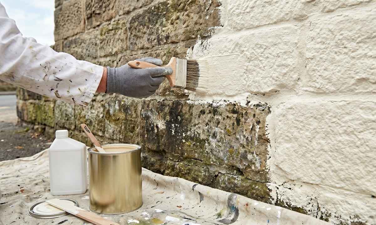 Painter applying microporous masonry paint to a Yorkshire stone wall in Bradford with a wide brush