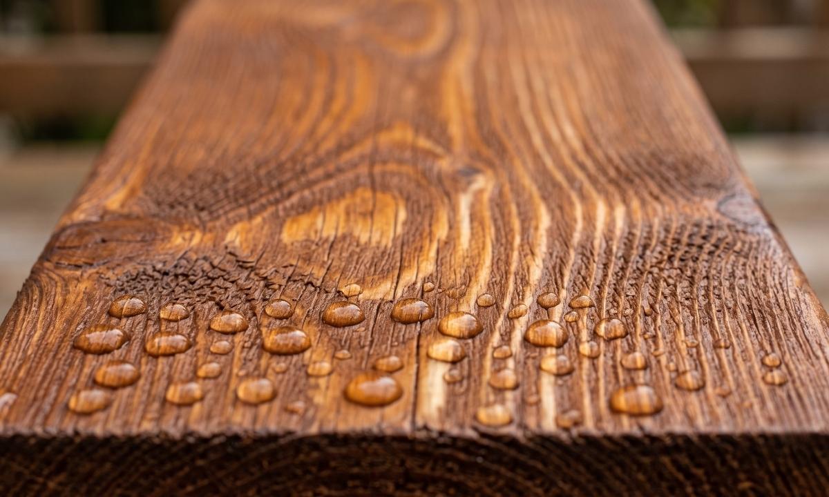 Close-up of semi-transparent deck stain showing wood grain texture and water beading